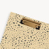 close up of tan and brown pattern clipfolio with gold clip on a cream background