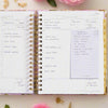 open book planner, written on pages, lined sticky note, beige background, pink flowers, gold accessories