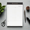 notepad with black trim on gray background, succulent, scissors, pens, wood accent