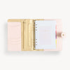 Blush binder open to show blush and gold interior with pockets and zipper and colorful starter pack insert pages
