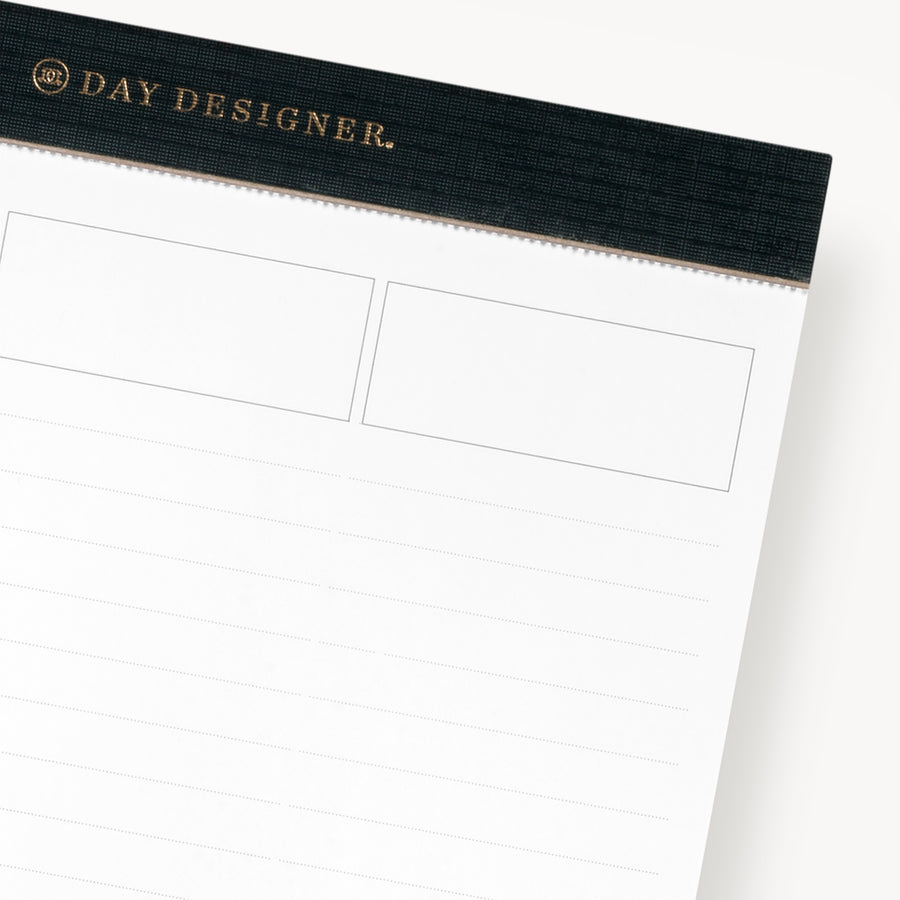 Planning pad with black and gold trim with lined notepad shown in close up 