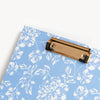 close up of blue floral clipfolio with gold clip  on a cream background