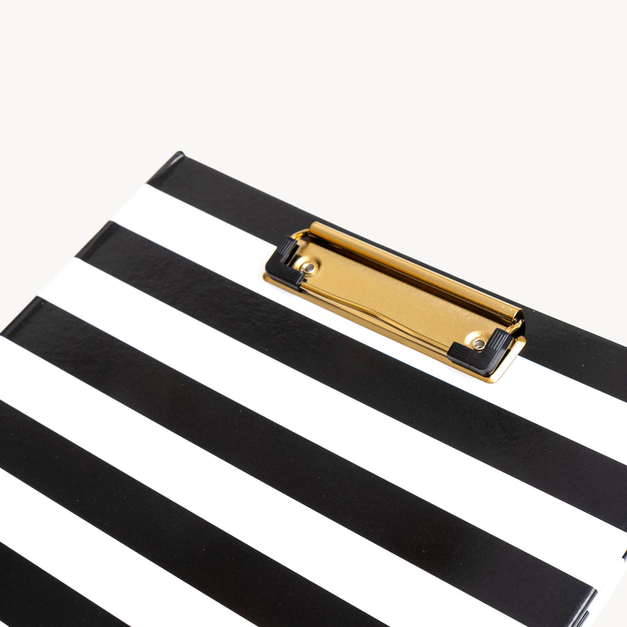 close up of a black and white pattern clipfolio with gold clip on a cream background
