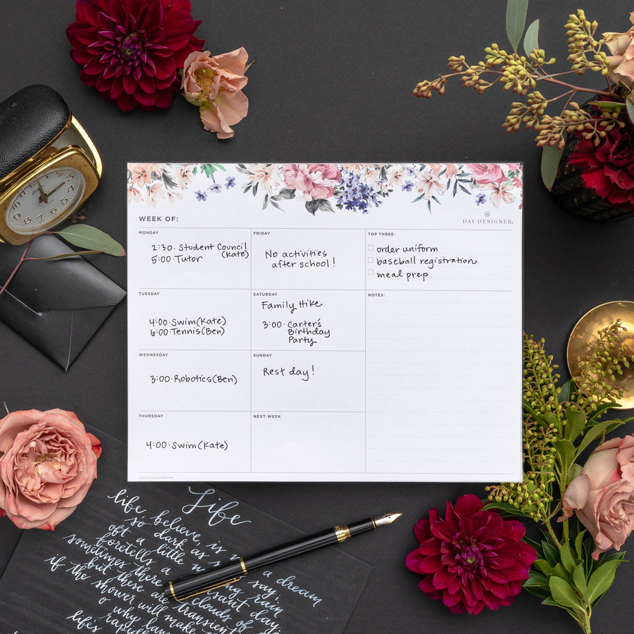 weekly planning pad with a floral illustration on a dark gray  background