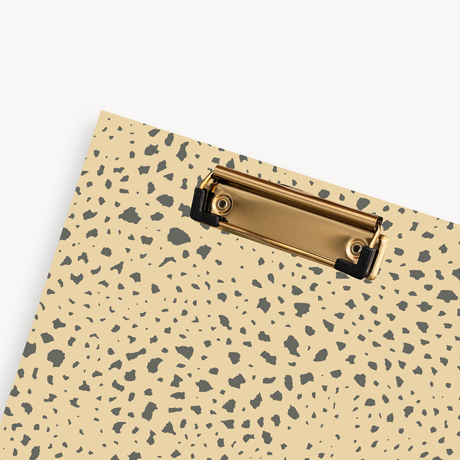 close up of tan and brown pattern clipfolio with gold clip on a cream background 