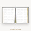 An open spiral-bound planner showing a 12-month calendar overview layout on white pages, with gold ring binding and gold page edges, centered on a light gray background. Text below reads '12-MONTH OVERVIEW'.