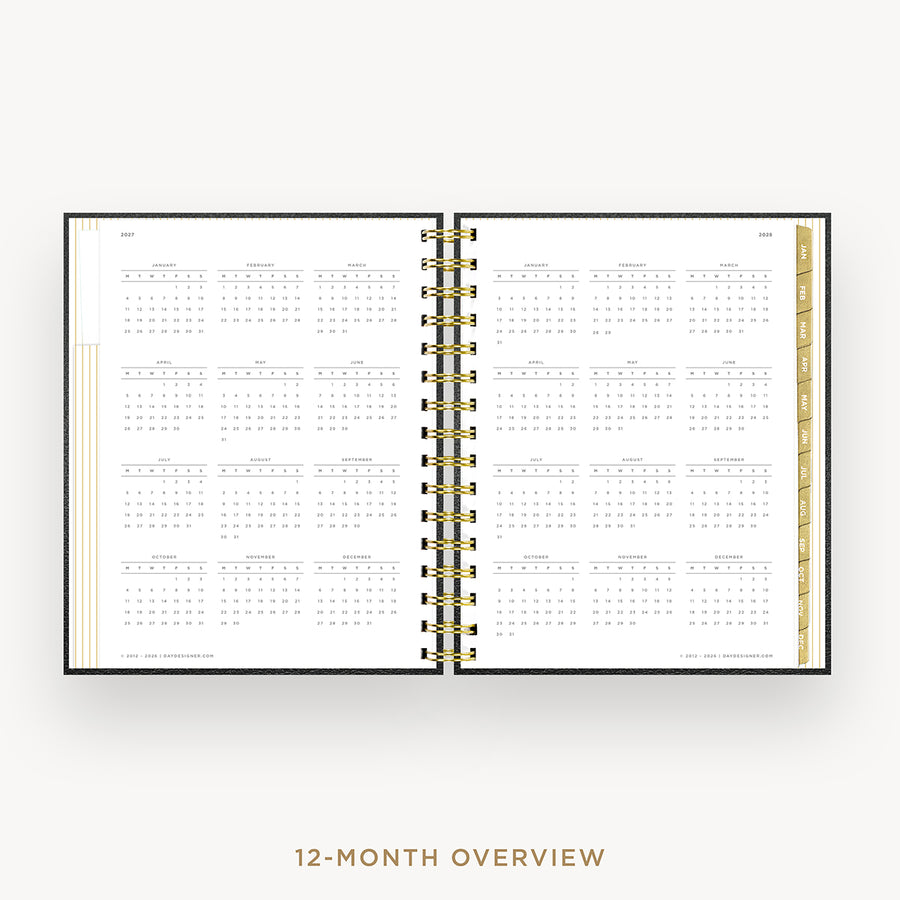 An open spiral-bound planner showing a 12-month calendar overview layout on white pages, with gold ring binding and gold page edges, centered on a light gray background. Text below reads '12-MONTH OVERVIEW'.