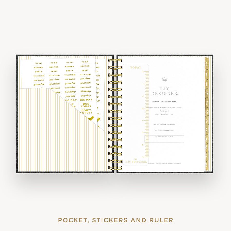 An open spiral-bound planner or pocket organizer shown from above on a light gray background. The pages are white with gold text, gold measurement rulers, and gold striped accents.