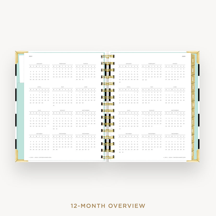 An open 12-month overview planner spread on a light gray background, showing white pages with black calendar grids and gold-toned binding rings. The left page border has a pale mint green accent, and the bottom of the image includes the text '12-MONTH OVERVIEW'.