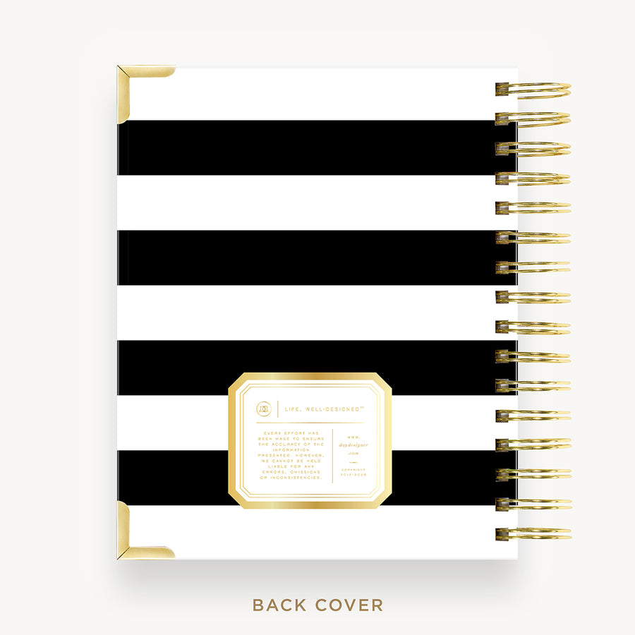 A spiral-bound planner or notebook shown from the back cover, featuring bold horizontal black and white stripes with gold corner accents and a gold-bordered label area. The right side shows a gold spiral binding.