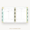 An open daily planner spread showing two lined daily planning pages with gold spiral binding and pastel accent tabs, photographed on a light gray background with the text 'DAILY PLANNING PAGE' below.