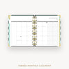 An open tabbed monthly calendar planner on a light gray background, showing a January 2027 calendar spread with gold spiral binding and pastel page accents. Text below reads 'TABBED MONTHLY CALENDAR'.