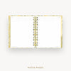 An open spiral-bound planner or notebook with lined white pages, shown against a light gray background. The cover has a subtle yellow and green floral pattern, and the pages are labeled 'NOTES PAGES' below.