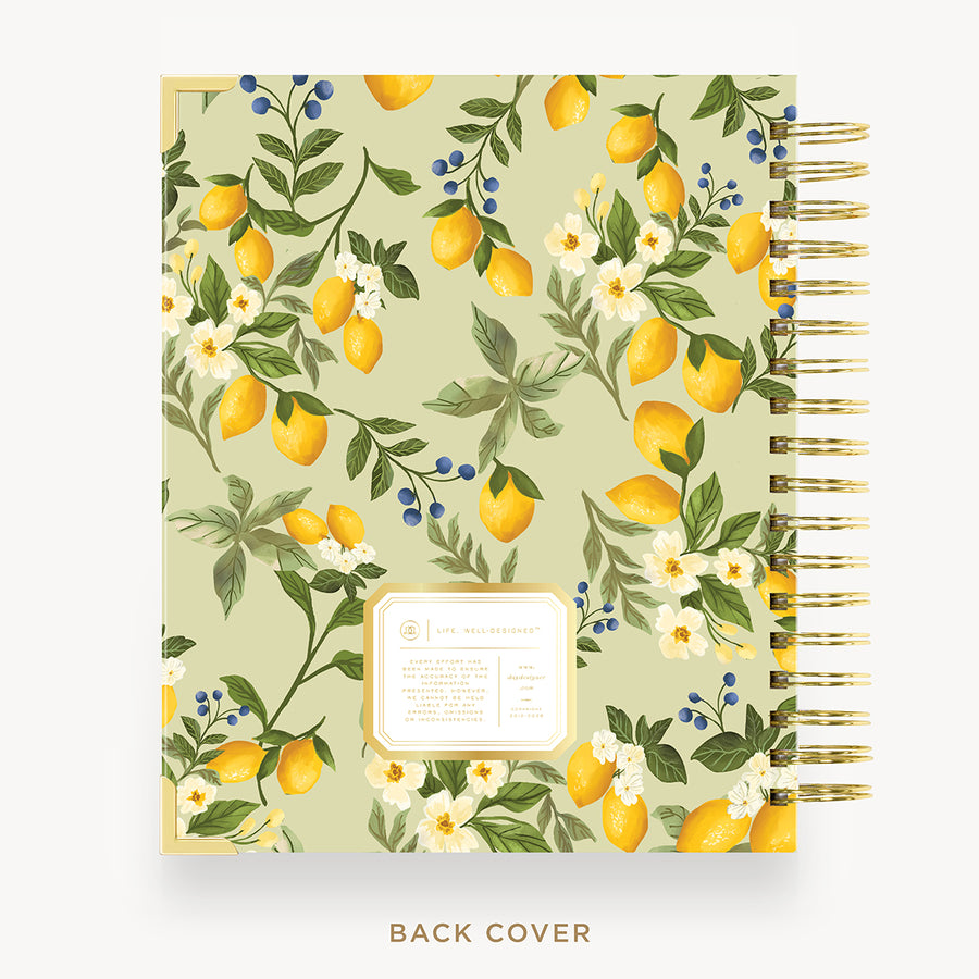 A spiral-bound notebook shown from the back cover, featuring a botanical pattern of lemons, white flowers, blue berries, and green leaves on a pale sage background. The notebook has a gold spiral binding and is displayed on a clean white background with the text 'BACK COVER' underneath.