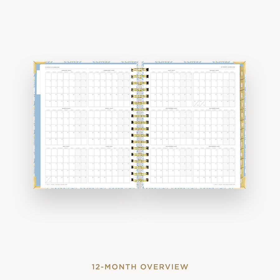 An open spiral-bound 12-month planner or calendar showing a monthly overview layout, photographed on a light gray background with the text '12-MONTH OVERVIEW' below.