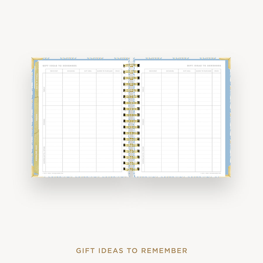 An open spiral-bound planner or notebook with a gift ideas to remember grid layout, shown on a light gray background with the text 'GIFT IDEAS TO REMEMBER' below.