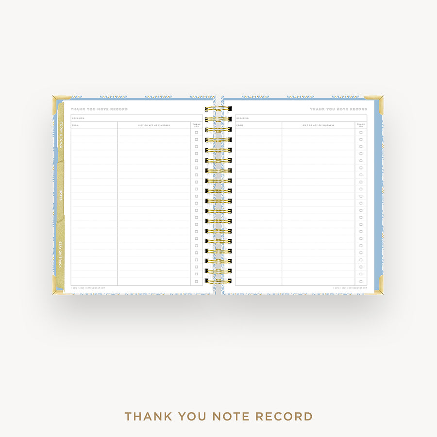 An open spiral-bound thank you note record planner with lined pages, gold rings, and a light blue and gold cover, shown on a light gray background with the text 'THANK YOU NOTE RECORD' below.