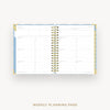 An open weekly planner page with lined layout sections, bound by a gold spiral, shown on a light gray background with the text 'WEEKLY PLANNING PAGE' below.