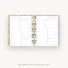 An open checklist planner with two inner pages titled 'ENTERTAINMENT CHECKLIST,' shown on a light gray background. The planner has a pastel floral border and gold spiral binding.
