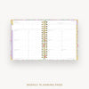 An open spiral-bound weekly planner showing white weekly planning pages with multicolored floral-patterned borders and gold-toned ring binder hardware, centered on a light gray background with the text 'WEEKLY PLANNING PAGE' below.