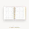 An open spiral-bound planner showing a 12-month calendar overview page, with a light pink cover and gold-toned binding, on a clean off-white background. Text below reads '12-MONTH OVERVIEW'.