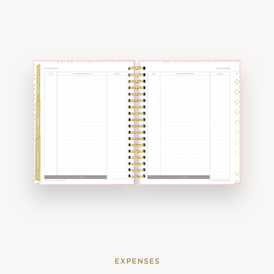 An open spiral-bound planner showing the expenses page with lined columns, gold ring binding, and a light pink cover, centered on a light gray background with the word EXPENSES below.