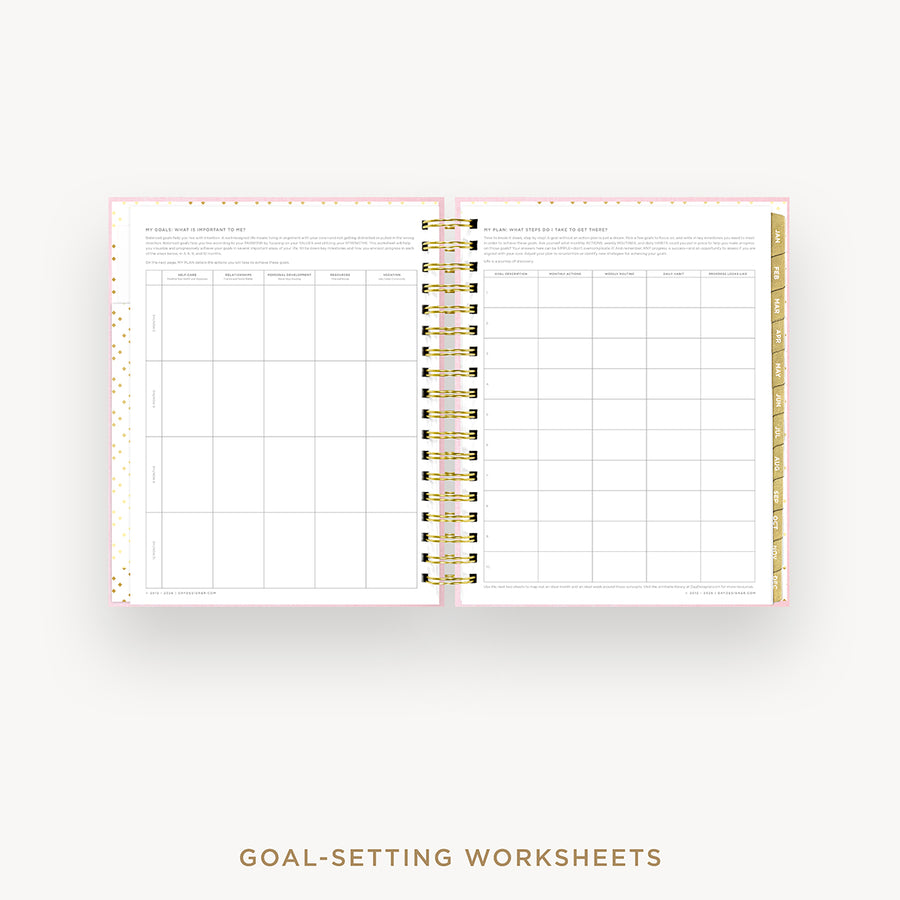 An open spiral-bound planner or notebook showing two printed goal-setting worksheet pages, with a gold ring binder and decorative pink and gold patterned edges, on a light gray background. Text below reads 'GOAL-SETTING WORKSHEETS'.