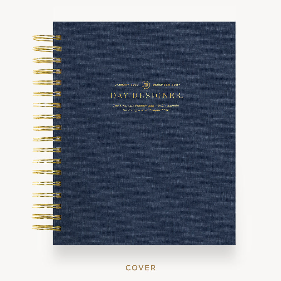 A navy blue spiral-bound planner cover with gold wire binding and gold foil text reading 'DAY DESIGNER.' on a clean white background.
