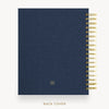 A navy blue spiral notebook with a textured fabric cover and gold wire binding, shown from the back cover side against a light background with the text 'BACK COVER' below.