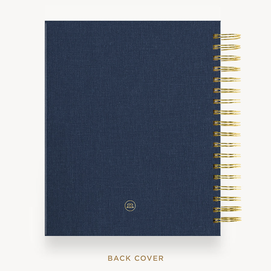 A navy blue spiral notebook with a textured fabric cover and gold wire binding, shown from the back cover side against a light background with the text 'BACK COVER' below.