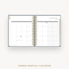 An open spiral-bound monthly calendar planner on a light gray background, showing a January 2027 page spread with tabbed monthly inserts and gold wire binding. Text below reads 'TABBED MONTHLY CALENDAR'.