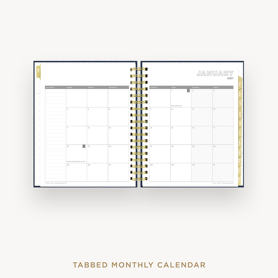 An open spiral-bound monthly calendar planner on a light gray background, showing a January 2027 page spread with tabbed monthly inserts and gold wire binding. Text below reads 'TABBED MONTHLY CALENDAR'.