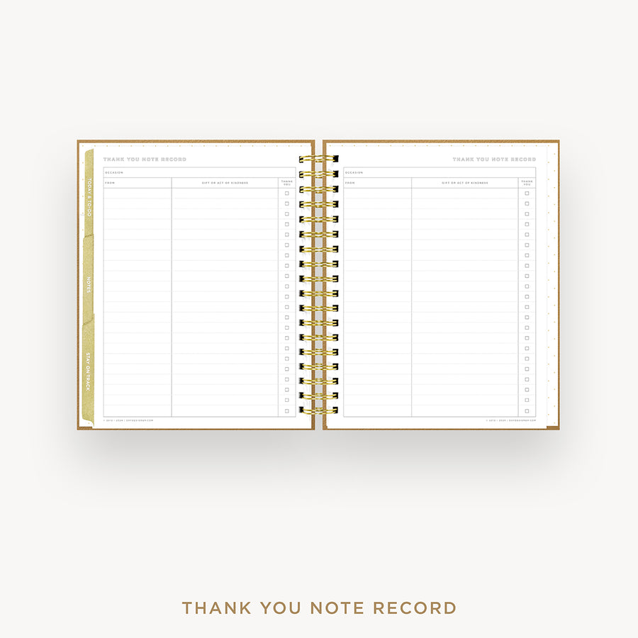 An open spiral-bound thank you note record planner on a light gray background, with gold-toned binding and gold text reading 'THANK YOU NOTE RECORD' below.