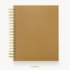 A tan textured spiral notebook with gold wire binding and gold foil lettering on the cover, shown against a white background with the word 'COVER' printed below.