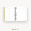An open spiral-bound planner or notebook showing a gold-toned 'Bucket List' page spread on both sides, photographed on a clean white background with the words 'BUCKET LIST' centered below.