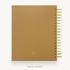 A tan textured notebook or planner shown from the back, with a gold spiral binding along the right edge and the words 'BACK COVER' printed below on a white background.