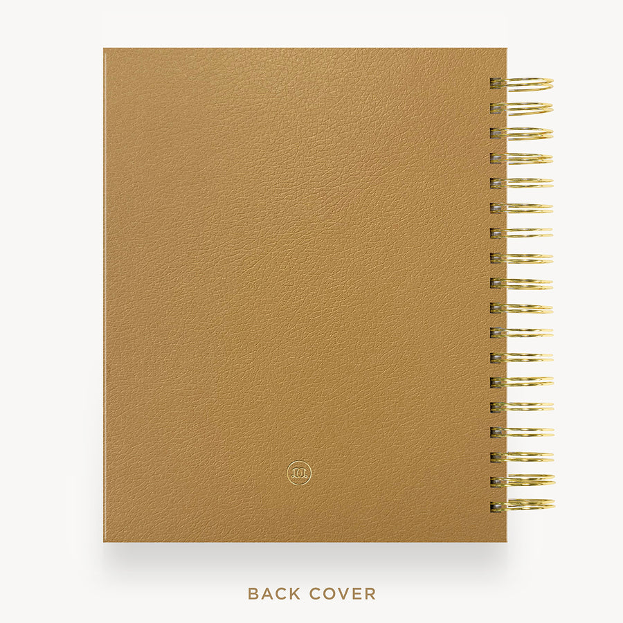 A tan textured notebook or planner shown from the back, with a gold spiral binding along the right edge and the words 'BACK COVER' printed below on a white background.