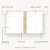 An open spiral-bound weekly planner page shown on a light gray background with callout lines labeling sections such as top 3 priorities, weekly quote, notes, schedule, to-do list, and includes weekends.