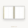 An open spiral-bound bucket list planner shown from above on a light gray background, with gold text reading 'BUCKET LIST' below.