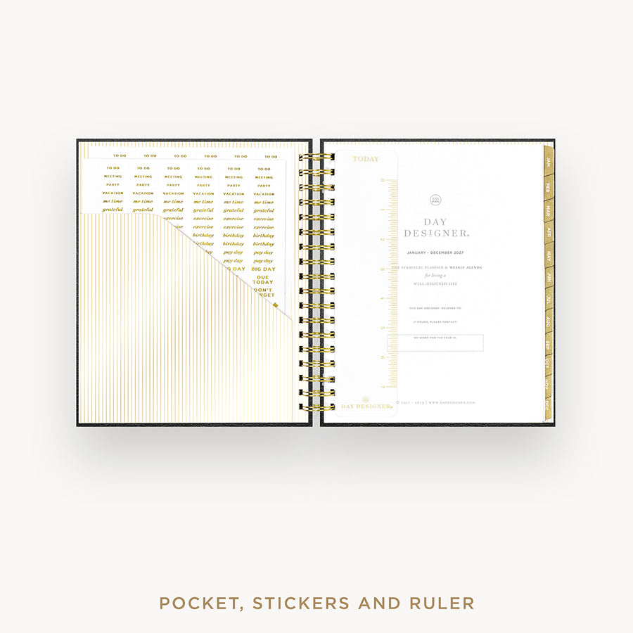 An open spiral-bound planner or pocket organizer shown on a light gray background, with gold-toned printed calendar and planner pages visible on both sides. Text below reads 'POCKET, STICKERS AND RULER'.