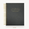 A black textured spiral-bound planner or journal shown closed, with gold wire binding and gold foil text on the cover reading 'DAY DESIGNER.' The cover is centered on a light gray background, with the word 'COVER' printed below.