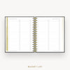 An open spiral-bound planner or notebook showing a bucket list page layout with lined sections and checkboxes, photographed on a light neutral background with the words 'BUCKET LIST' below.