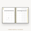 An open tabbed monthly calendar planner shown from above on a light gray background. The pages are white with gray grid headers and gold-toned spiral binding down the center.