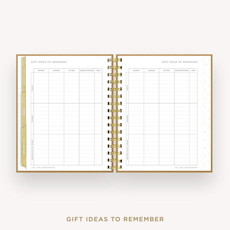 An open spiral-bound gift planner or notebook with gold rings, white pages, and gold-toned tabbing, shown on a light gray background with the text 'GIFT IDEAS TO REMEMBER' below.