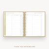 An open spiral-bound thank you note record planner on a light gray background. The pages are white with gold lines and gold tabs, and the gold metal spiral binding is clearly visible.