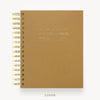 A tan textured spiral notebook with gold wire binding and gold foil lettering on the cover, shown on a clean white background with the word 'COVER' printed below.