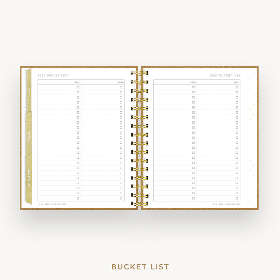 An open spiral-bound bucket list planner on a light gray background. The pages are white with gold lines and gold ring binder hardware, featuring lined sections with checkboxes labeled for daily, weekly, monthly, and yearly goals.
