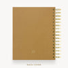 A tan textured spiral notebook shown from the back, featuring a gold-tone spiral binding and a small circular logo near the bottom. The text 'BACK COVER' is printed below the notebook on a clean white background.