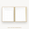 An open spiral-bound planner or notebook showing two pages of goal-setting worksheets, with a gold wire binding and gold border lines, on a light gray background. Text below reads 'GOAL-SETTING WORKSHEETS'.