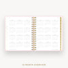 An open spiral-bound planner showing a 12-month calendar overview layout on white pages with a light pink border and gold accents, centered on a light gray background with the text '12-MONTH OVERVIEW' below.